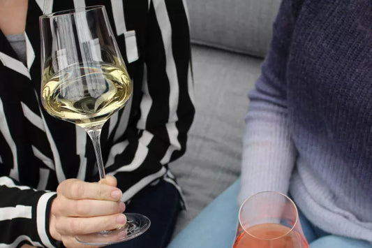 Person holding white wine glass in striped shirt